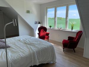 a bedroom with two red chairs and a bed and windows at Villa Baldringe in Ystad +21 photos