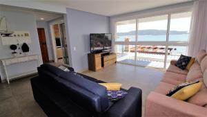 sala de estar con sofá y TV en 1080 - Apartamento com vista para o mar em Bombinhas, en Bombinhas