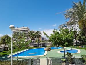 a large swimming pool with trees and buildings at Apartamento con vistas al mar in Alicante +9 photos