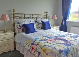 a bedroom with a bed with blue pillows at Mary Naoise Holiday Home in Lettermacaward