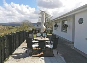 a table and chairs on the patio of a house at Mary Naoise Holiday Home in Lettermacaward