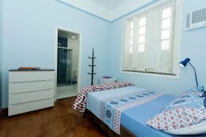een blauwe slaapkamer met een bed en een raam bij Casa Saga - All Suites in Rio de Janeiro