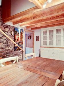 ein Esszimmer mit einem Holztisch und einer Steinwand in der Unterkunft O Recanto do Atlantico in Viveiro