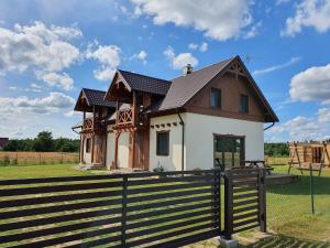 una casa in un campo con una recinzione di MILOCHÓWKA - dom drewniany bliźniak a Wdzydze Tucholskie