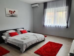 a bedroom with a bed with red pillows and a red rug at Flamingo Apartment in Sárvár +2 photos
