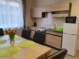 a kitchen with a table with chairs and a refrigerator at Flamingo Apartment in Sárvár