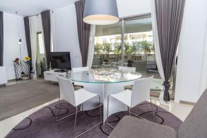 a living room with a glass table and white chairs at Praia da Rocha Edifício Foz Palace t2 in Portimão