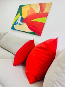 two red pillows on a white couch with a painting at Entire apartment in Lisbon plus Car in Lisbon