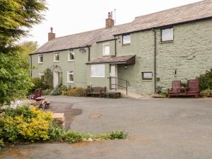 a green building with benches in front of it at Near Bank Cottage in Corney