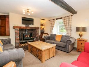 a living room filled with furniture and a fireplace at Near Bank Cottage in Corney