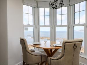 a dining room with a table and chairs and windows at Sennen Heights in Sennen Cove