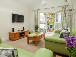 a living room with a green couch and a tv at Seabien in Falmouth