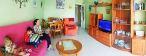 卡爾佩的住宿－Apartamentos Esmeralda 2，两个女孩坐在客厅的粉红色沙发上