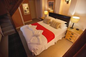 - une chambre avec un grand lit et des serviettes dans l'établissement Burnthwaite Cottage, à Windermere