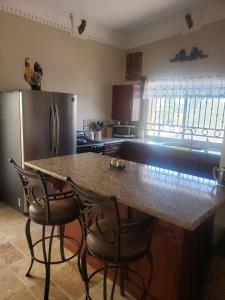 a kitchen with a counter with chairs and a refrigerator at Maria's Place, Puerto Peñasco, Oriente in Puerto Peñasco