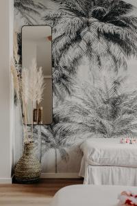 a bedroom with a mirror and a palm tree wallpaper at Hôtel PALMITO in Biarritz