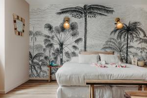 a bedroom with a bed with palm trees wallpaper at Hôtel PALMITO in Biarritz