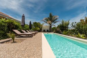 einen Pool mit Stühlen und einem Sonnenschirm neben einem Haus in der Unterkunft MontePico in Grândola