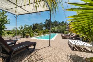 a pool with chaise lounge chairs and an umbrella at MontePico in Grândola
