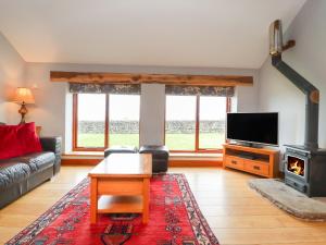 uma sala de estar com um sofá, uma televisão e uma lareira em Ingleborough Barn em Lancaster