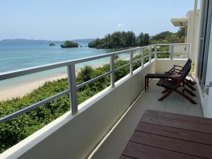 a balcony with a bench and a view of the beach at Ocean Front SUMUIDE in Nago