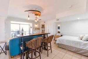 1 dormitorio con 1 cama y cocina con mesa en Stunning Ocean Views STEPS from the Beach with Pool! Fabulous 4th Floor Studio!, en New Smyrna Beach