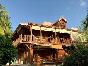 a large wooden house with a balcony and trees at Banan Woz in Bouillante