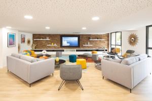 a living room with couches and a tv on a brick wall at Résidence SWEETLY Saint Augustin in Bordeaux