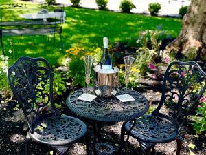 Buttonwood Boutique Hotel في West Cape May: طاولة مع زجاجة من النبيذ وكرسيين