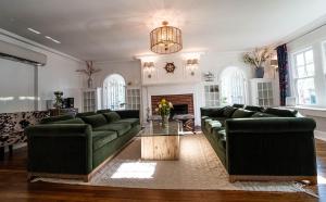 a living room with green couches and a table at Buttonwood Boutique Hotel in West Cape May