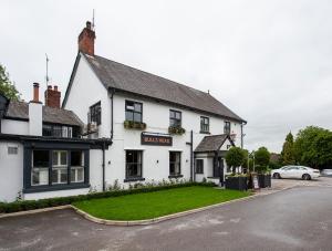 a white building with a green lawn in front of it at The Bulls Head Hotel in Hale