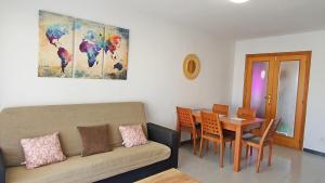 - un salon avec un canapé et une table avec des chaises dans l'établissement LAS GARDENIAS GANDIA - Alquiler Familias, à Puerto de Gandía