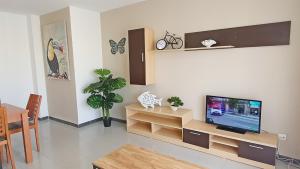 sala de estar con TV de pantalla plana en la pared en LAS GARDENIAS GANDIA - Alquiler Familias, en Puerto de Gandía