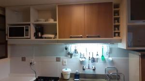uma cozinha com armários de madeira e utensílios na parede em GringsApsAluguel204 em Gramado