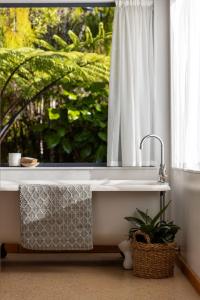 a bath tub in a bathroom with a window at Karu ō te Kiwi - Your Enchanting Hideaway in Pakawau