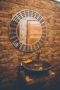 lavabo en el baño con espejo en una pared de ladrillo en Satria Bungalow, en Uluwatu
