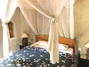 een slaapkamer met een hemelbed bij Satria Bungalow in Uluwatu