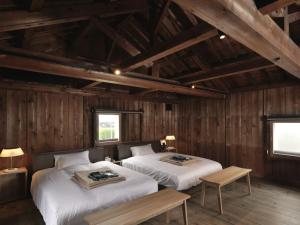 Duas camas num quarto com paredes de madeira em HOTEL CULTIA DAZAIFU em Dazaifu