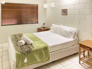 a bedroom with a bed with white sheets and a window at Alma Bay Holiday Unit 4 in Arcadia