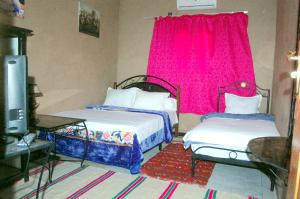 two beds in a room with a pink window at Maison d'Hôtes Ghalil in Ouarzazate