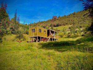 una casa gialla su una collina in un campo di Cabaña Agrreste a Nemocón