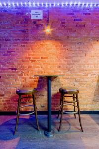 a table and two stools in front of a brick wall at Lucky D's Youth and Traveler's Hostel in San Diego