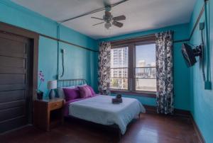 a bedroom with a bed with purple pillows and a window at Lucky D's Youth and Traveler's Hostel in San Diego