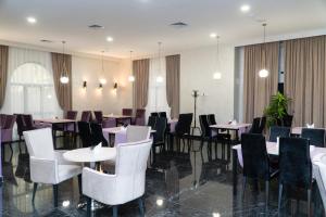 a dining room with white tables and chairs at East Palace Hotel in Almaty