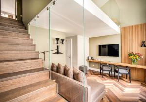 a living room with a couch and a tv and stairs at DBH – Boutique Hotel Lake Como in Como