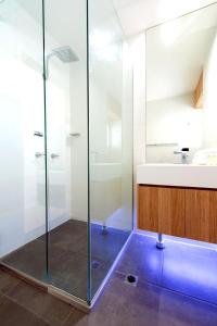 a bathroom with a glass shower and a sink at SandCastles Noosa in Noosa Heads