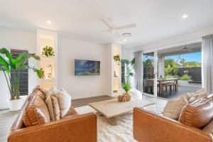 a living room with two couches and a table at Banksia - Lennox Head in Lennox Head