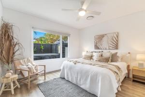 a white bedroom with a bed and a window at Banksia - Lennox Head in Lennox Head
