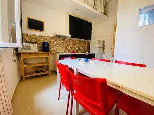 a kitchen with a white table and red chairs at Liolà Home Palermo in Palermo