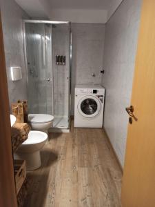 a bathroom with a shower toilet and a washing machine at Casa Dolomiti in Moena